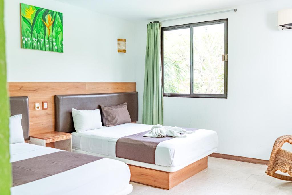 two beds in a room with a window at Hotel Cañada Internacional in Palenque