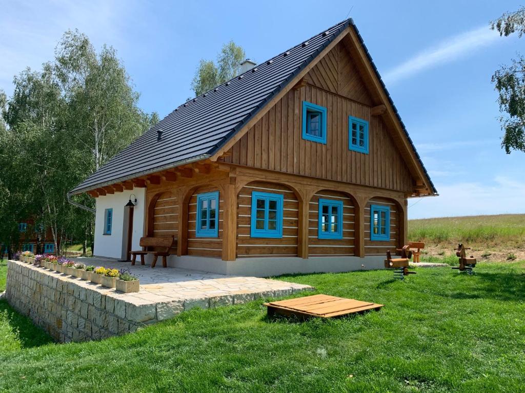 ein großes Holzhaus mit blauen Fenstern auf einem Feld in der Unterkunft Roubenka Kokořínsko in Dubá