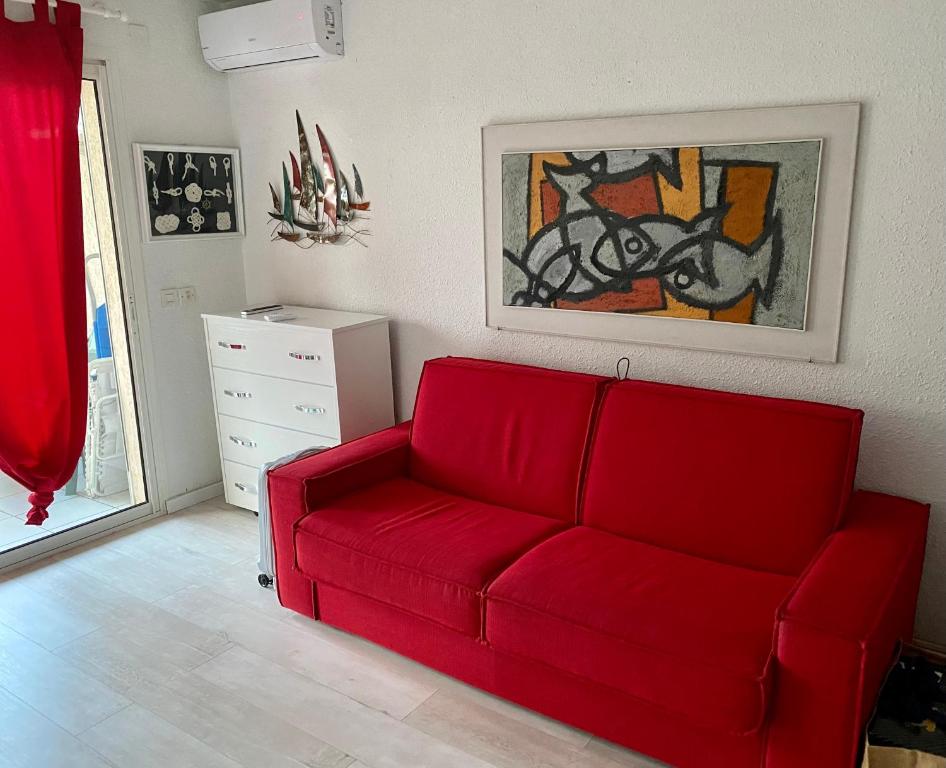 - un canapé rouge dans un salon avec un tableau dans l'établissement Corsica studio Face à la mer Moriani plage, à San-Nicolao