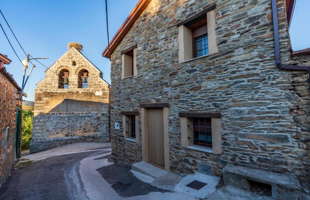 a stone building with a door and a church at Las Morales Casa Rural 