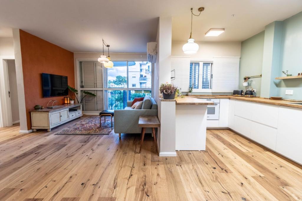 uma cozinha em plano aberto e sala de estar com pisos em madeira em נופש ליד הים בת גלים em Haifa