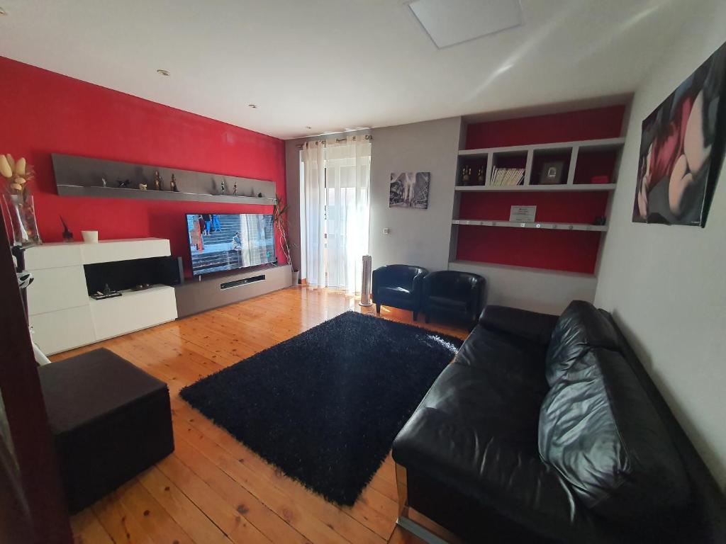 a living room with a black leather couch and red walls at Teo in Pamplona