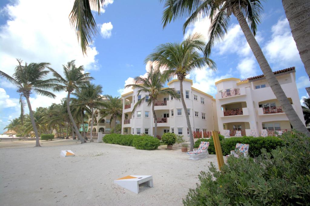 a building on the beach with palm trees and a bench at Miramar Villas Resort in San Pedro