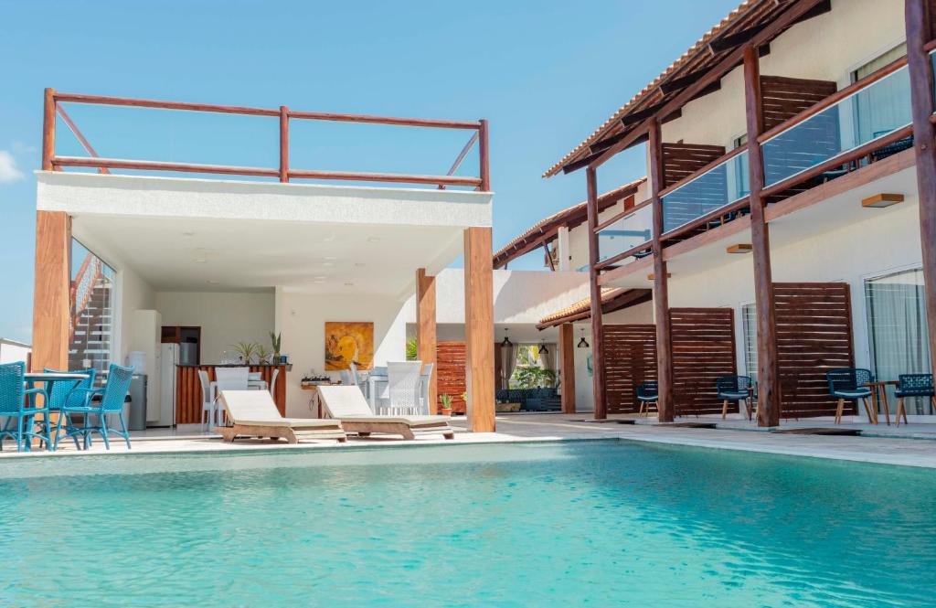 una piscina con sillas y una casa en Caly Pousada, en São Miguel do Gostoso