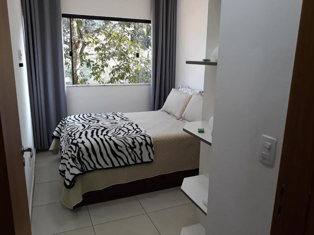 ein kleines Schlafzimmer mit einem Zebra-Bett und einem Fenster in der Unterkunft Aconchego e Requinte no Centro in Petrópolis