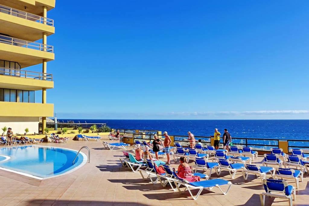 un grupo de personas sentadas en sillas junto a una piscina en 810 - Edif Aguamarina - Vacation Rental Home in the coast line of Golf del Sur, en San Miguel de Abona