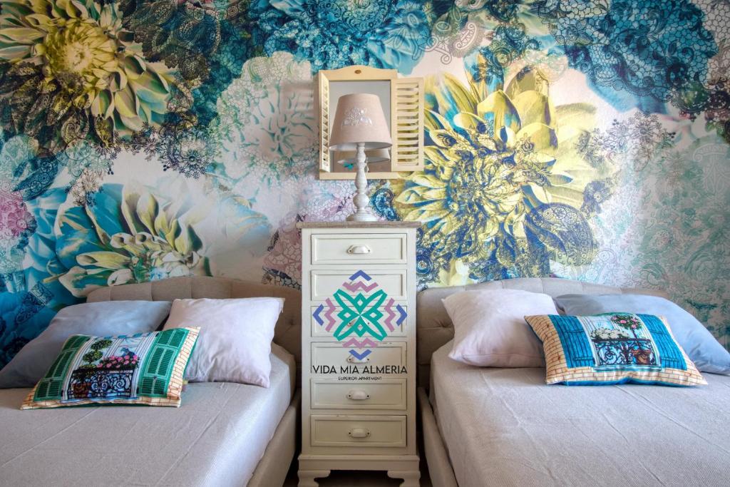 a bedroom with two beds and a wall with flowers at Vida Mia Almeria - Superior Apartment in Vera