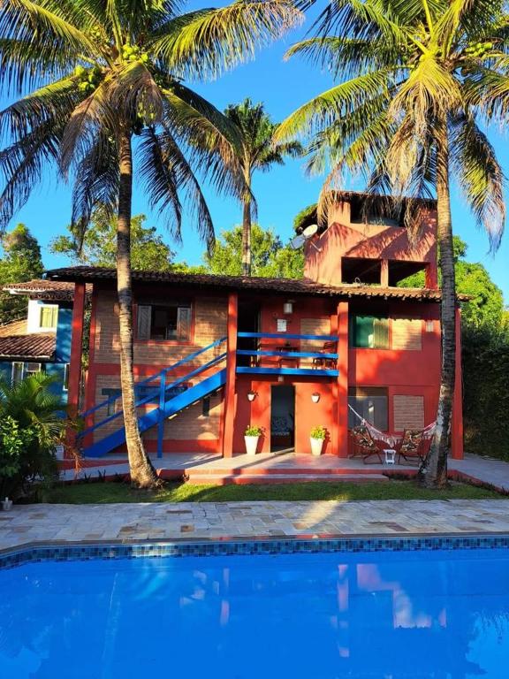 a house with palm trees in front of a swimming pool at Studio Taípe Arraial in Porto Seguro