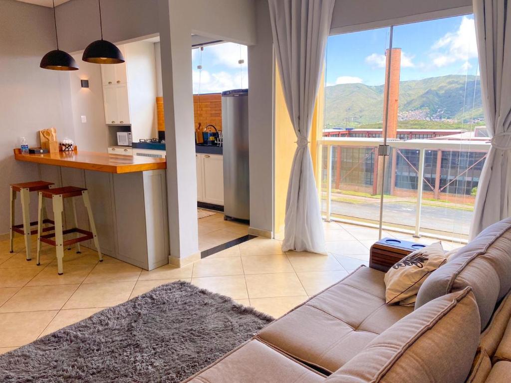 een woonkamer met een bank en een keuken bij Apartamento ao lado da UFOP com garagem in Ouro Preto