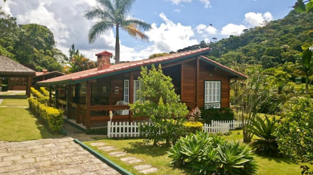 a small wooden house with a palm tree behind it at Chalé Canoas - Conforto na serra de Teresópolis in Teresópolis
