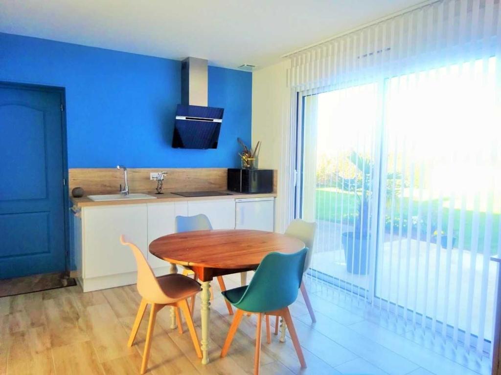 eine Küche mit einem Tisch und Stühlen sowie einer blauen Wand in der Unterkunft Gîte Saint-Georges-du-Bois, 2 pièces, 2 personnes - FR-1-410-336 in Rouillon