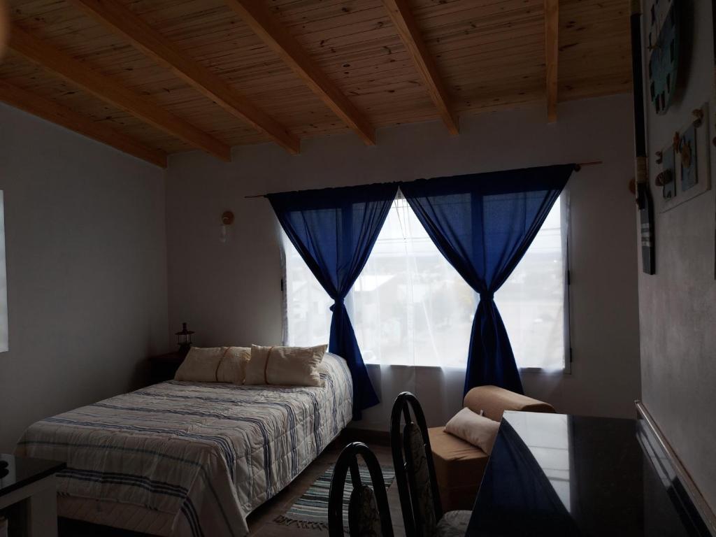 コモドーロ・リバダビアにあるLu-Marのベッドルーム1室(ベッド1台、青いカーテン付きの窓付)
