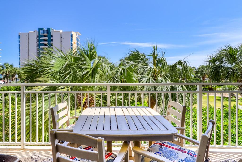 a wooden table and chairs on a balcony with palm trees at Sterling Shores 205 in Destin