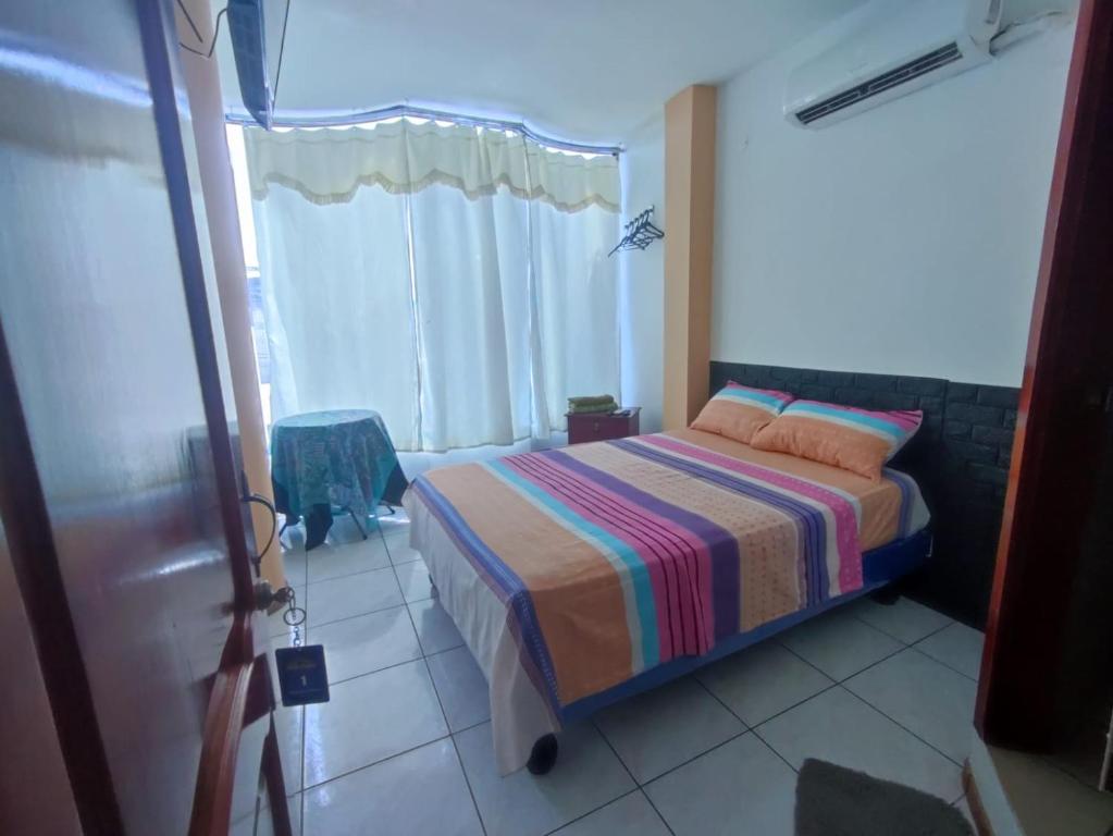 曼塔的住宿－Hostal Venecia -Tu casa en Manta.，一间卧室配有一张带条纹毯子的床和窗户