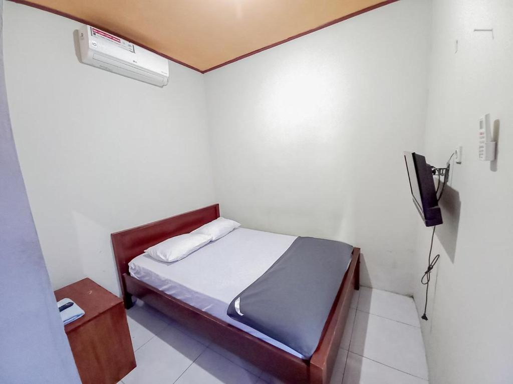 een kleine slaapkamer met een bed en een televisie bij Hotel Gerung 2 near Luwes Mall Nganjuk Mitra RedDoorz in Nganjuk