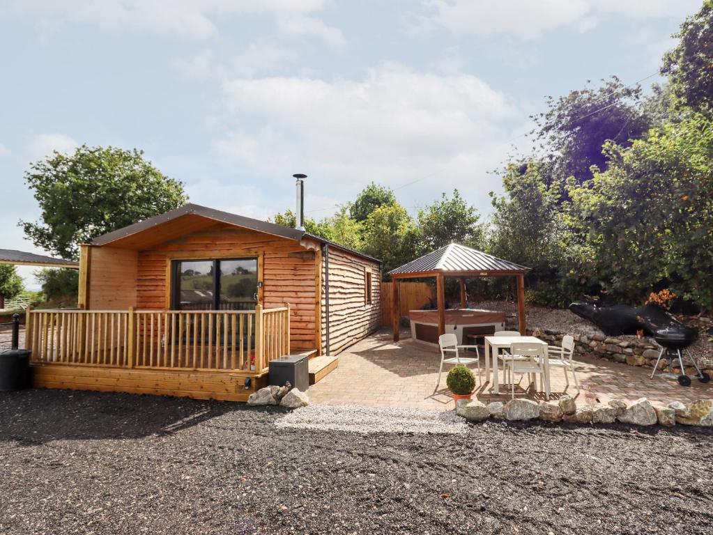 a log cabin with a table and a gazebo at Celyn in Ruthin