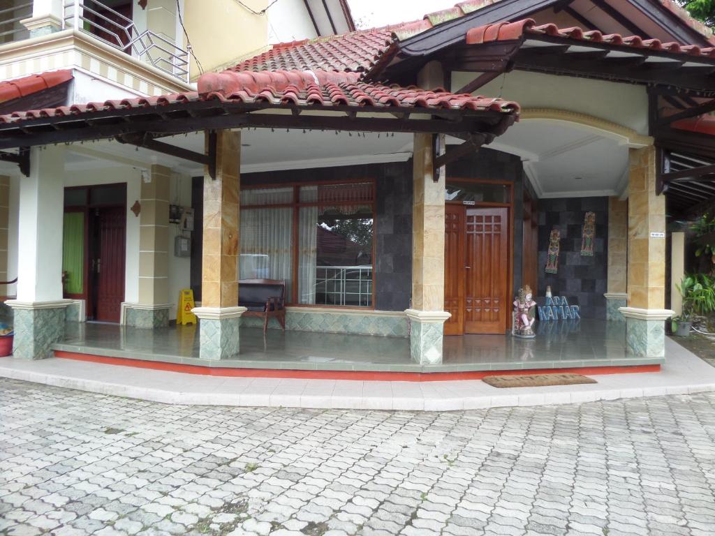 a building with a porch with a door and a dog in front at Sukapura Permai Hotel in Lambangkuning