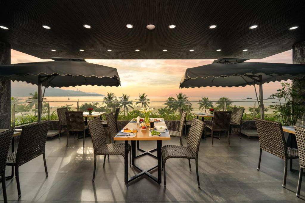 ein Restaurant mit einem Tisch, Stühlen und Sonnenschirmen in der Unterkunft Nguyen Gia Hotel in Đà Nẵng