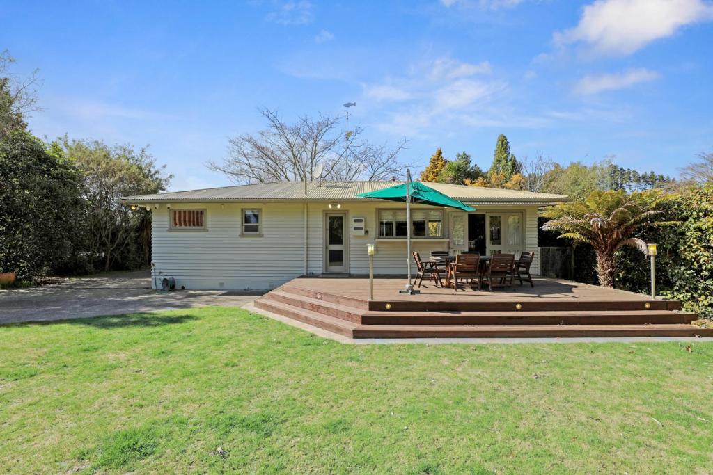 Cette maison dispose d'une terrasse avec une table et un parasol vert. dans l'établissement Pukeko Lodge - Tūrangi Holiday Home, à Turangi