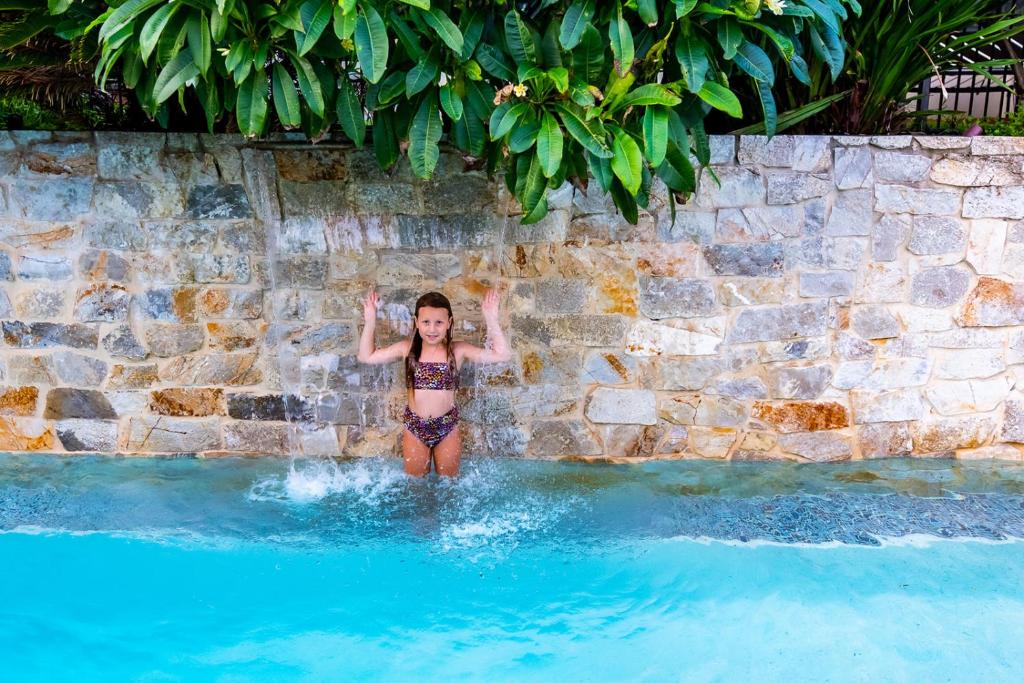 a young girl standing in the water in a swimming pool at Spectacular Bilgola Beachhouse in Avalon