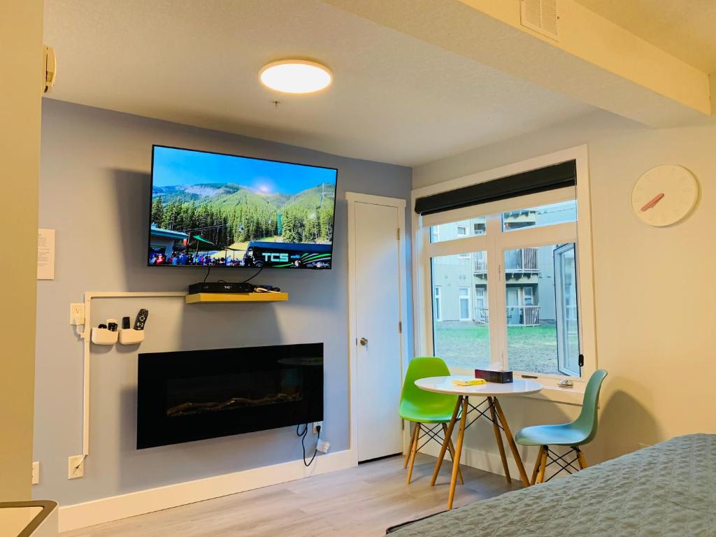 een kamer met een tv aan de muur en een tafel en stoelen bij A Romantic Studio with Full Kitchen & AC-141 in Canmore