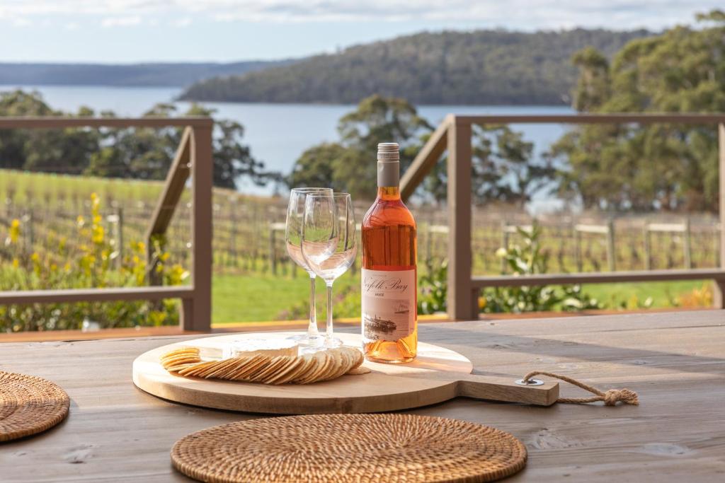 a bottle of wine and a glass on a table at Norfolk Bay Retreat - views over the sea and vines 