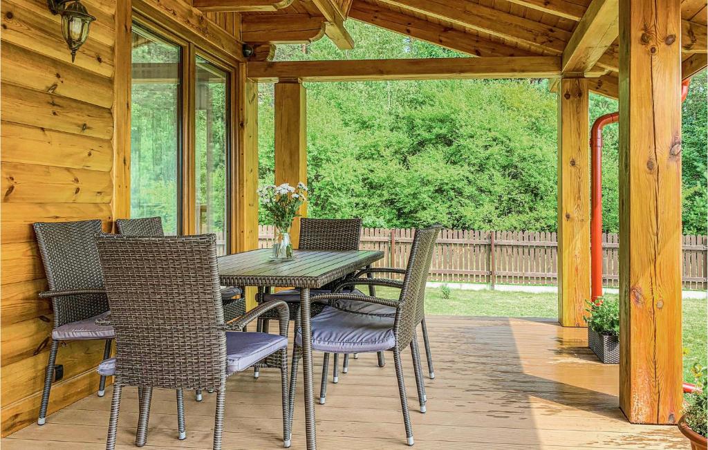 drewnianym patio ze stołem i krzesłami na ganku w obiekcie 4 Bedroom Amazing Home In Ruciane-Nida w mieście Karwica