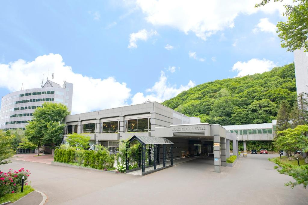 a large building with a hill in the background at Otaru Asari Classe Hotel in Otaru
