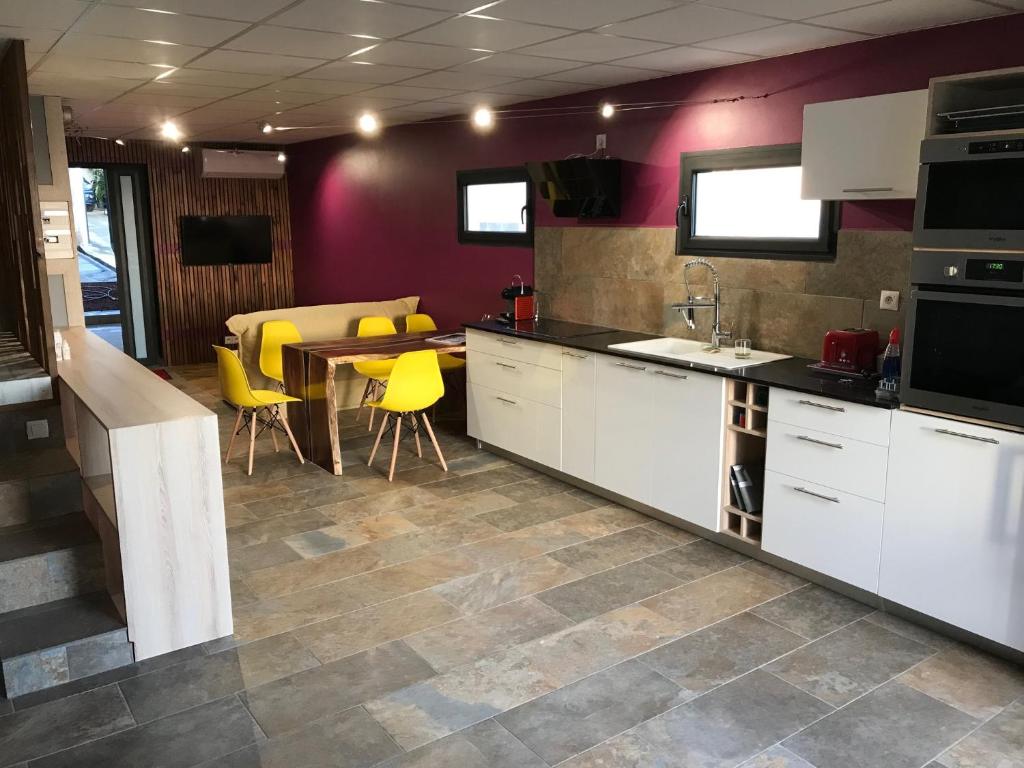 a kitchen with white cabinets and a table and yellow chairs at loft meublé fonctionnel proche de grande anse in Petite Île