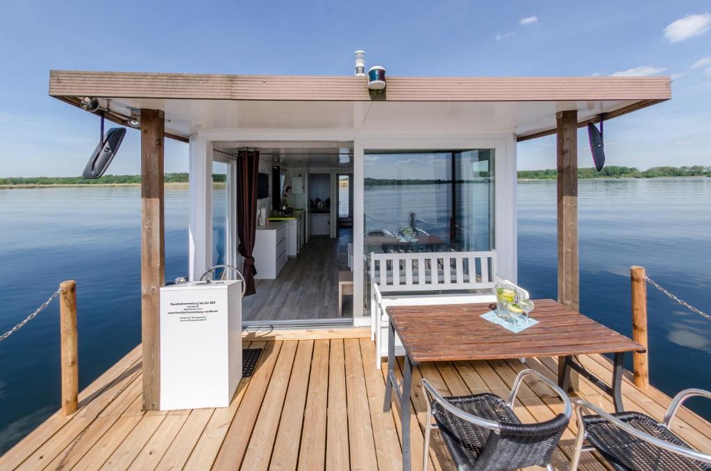 una terraza de madera con mesa y sillas sobre el agua en feststehendes Hausboot en Kolonie Zern