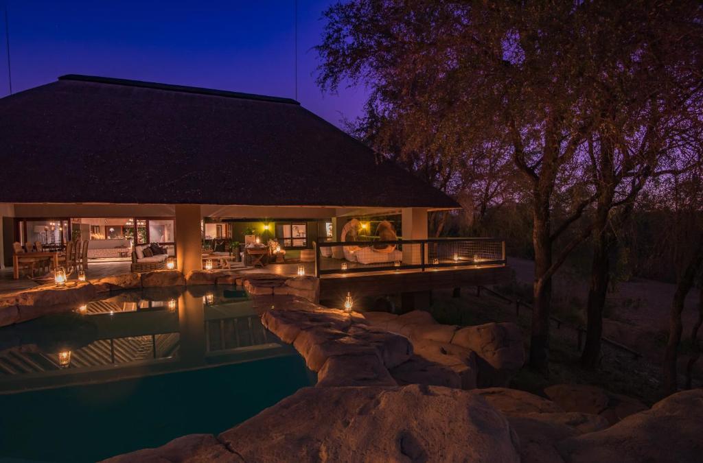 a house with a swimming pool at night at Simbavati River Sands in Timbavati Game Reserve