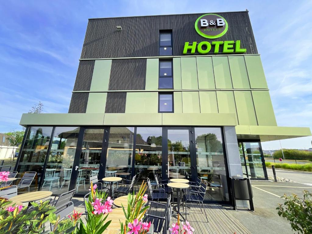 a hotel with tables and chairs in front of it at B&B HOTEL Compiègne in Compiègne