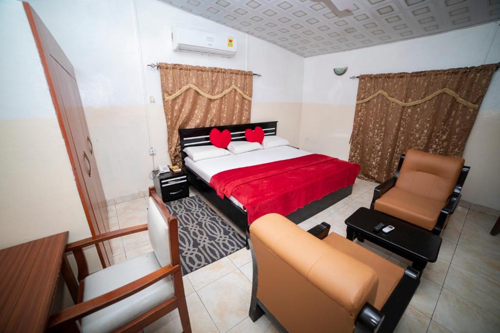 a bedroom with a bed and two chairs in it at Bombay Hotel in Accra