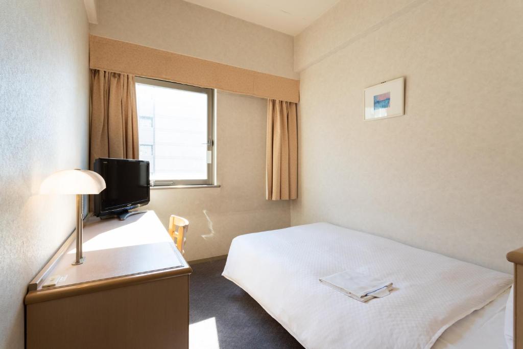 a hotel room with a bed and a television at Hotel South Garden Hamamatsu in Hamamatsu