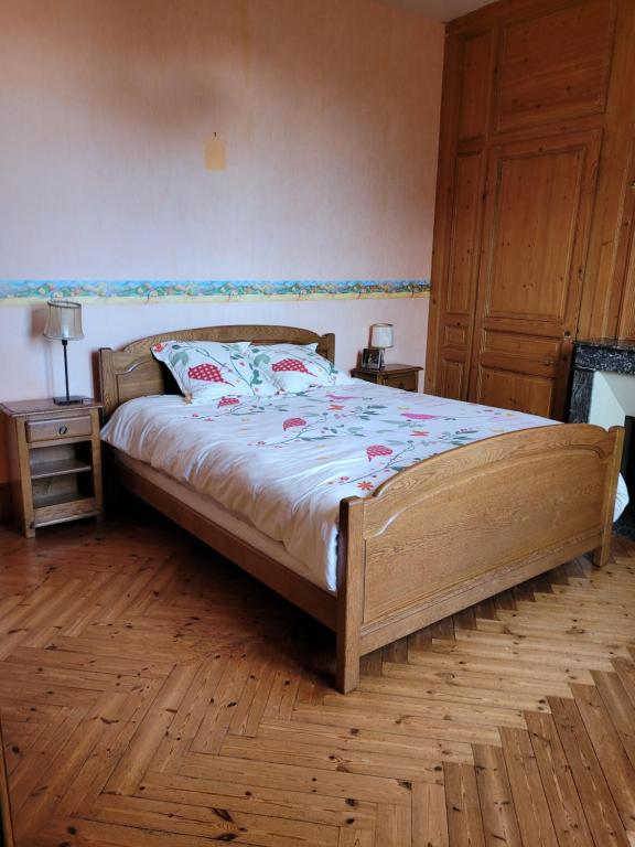 um quarto com uma cama de madeira e piso de madeira em Chambre chez l'habitant 3 em Biville-la-Baignarde