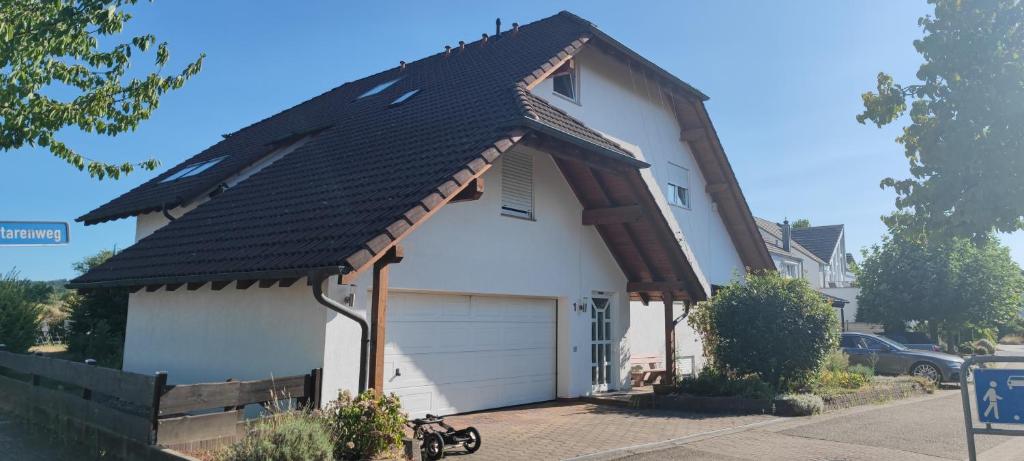 een wit huis met een gambrel dak en een garage bij Ferienwohnung zwischen Rhein und Schwarzwald in Bischweier