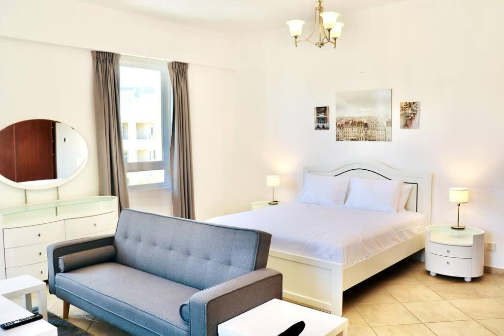 una camera con un letto e un divano blu di Unified Vacation Homes-Spacious Studio in lush green Motor City a Dubai