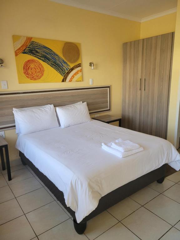 um quarto com uma cama grande e lençóis brancos em Mogale Royal Gardens em Polokwane