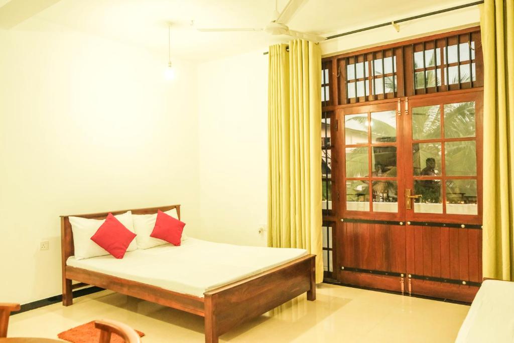a bedroom with a bed with red pillows at Cottage 23 in Kurunegala