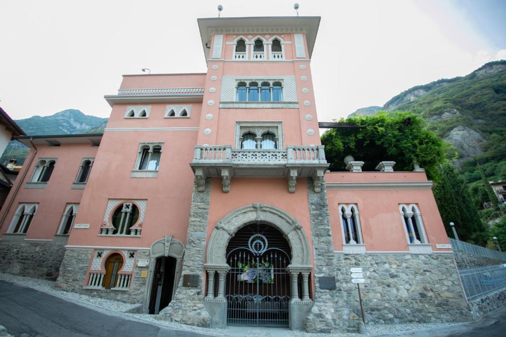 um edifício cor-de-rosa com uma torre de relógio numa rua em La Portineria Luxury B&B em Piancogno