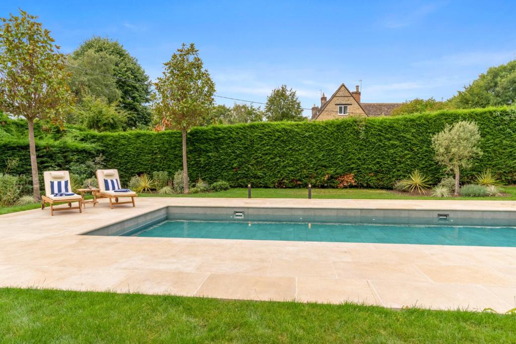 a swimming pool with two chairs in a yard at Barns Lee in Malmesbury