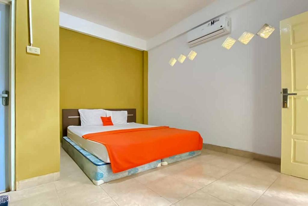 a bedroom with a bed with an orange blanket at KoolKost Syariah near Stasiun Tanjung Karang Lampung in Bandar Lampung