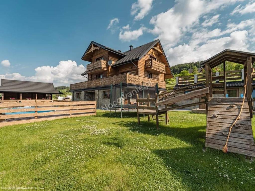 una grande casa in legno con un prato verde di fronte di Nurt Food Uroczysko Jaworki a Jaworki