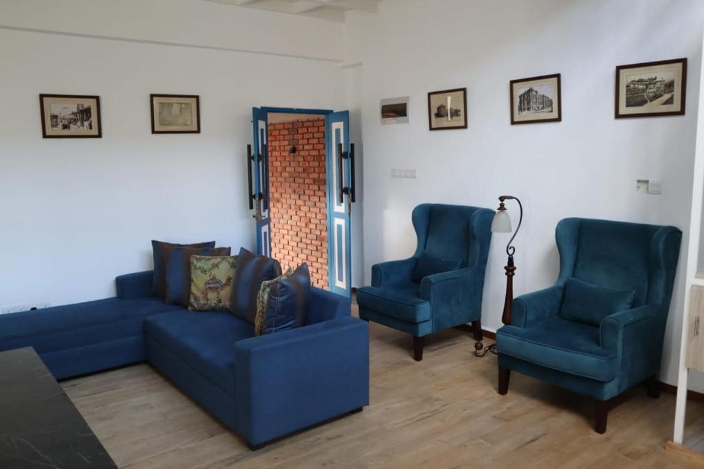 salon z 2 niebieskimi krzesłami i kanapą w obiekcie Alakamandava w Kolombo