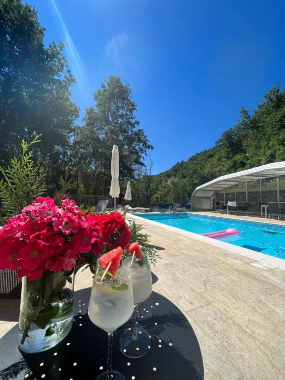 a table with two glasses and flowers next to a swimming pool at Le Boccede Country House B&B in Villa Minozzo