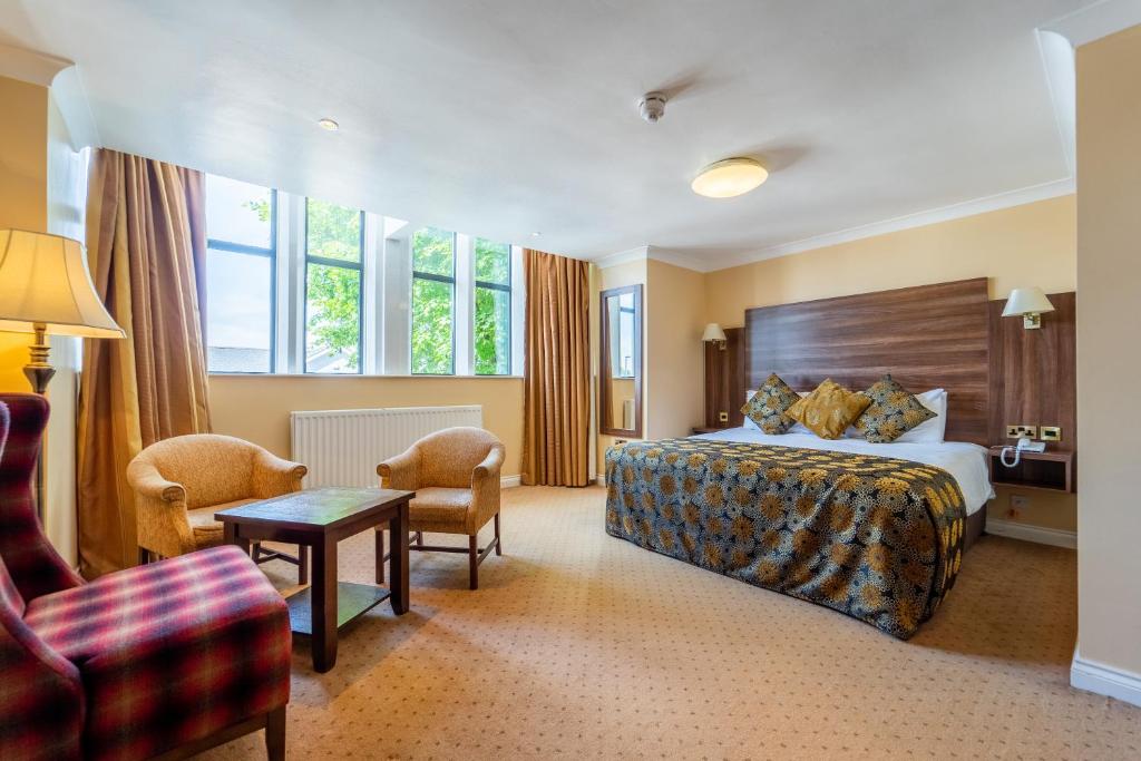 um quarto de hotel com uma cama, uma mesa e cadeiras em Adair Arms Hotel em Ballymena