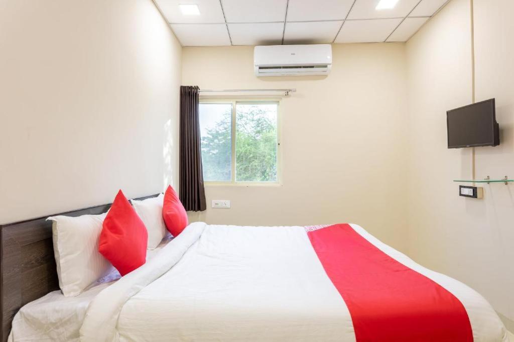 een slaapkamer met een bed met rode kussens en een raam bij JAGTARA RESIDENCY in Indore