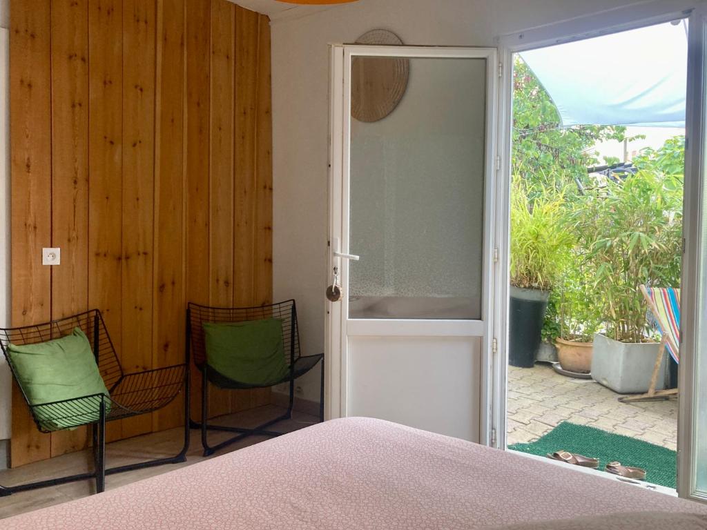 a bedroom with a bed and two chairs and a sliding glass door at Maisonnette studio Arcachon 300m plage in Arcachon