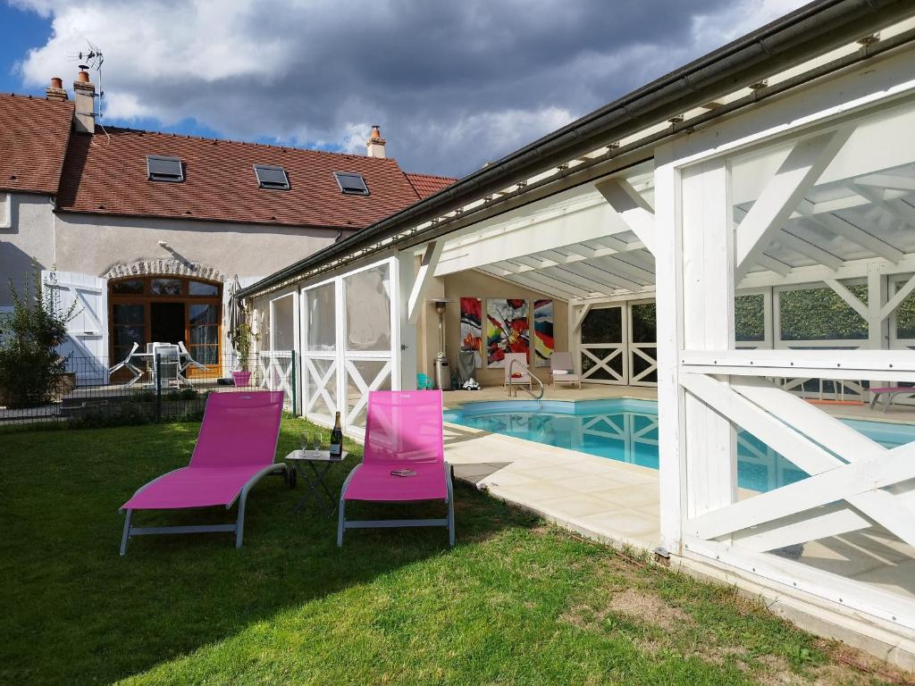 una casa con sedie rosa e una piscina di Bienvenue au Faré Hibiscus a Corrombles