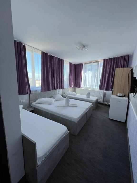a hotel room with two beds and windows at Hotel Miniom in Constanţa